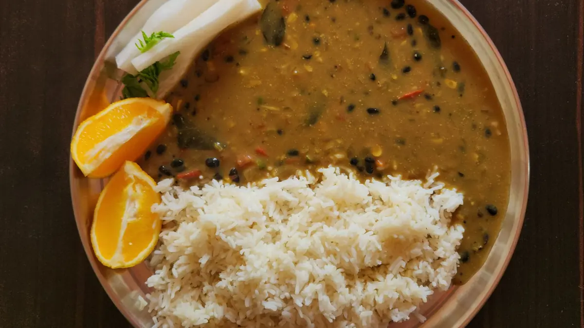 A steel plate of dal and rice with orange slices, a balanced everyday Indian meal instead of a crash diet