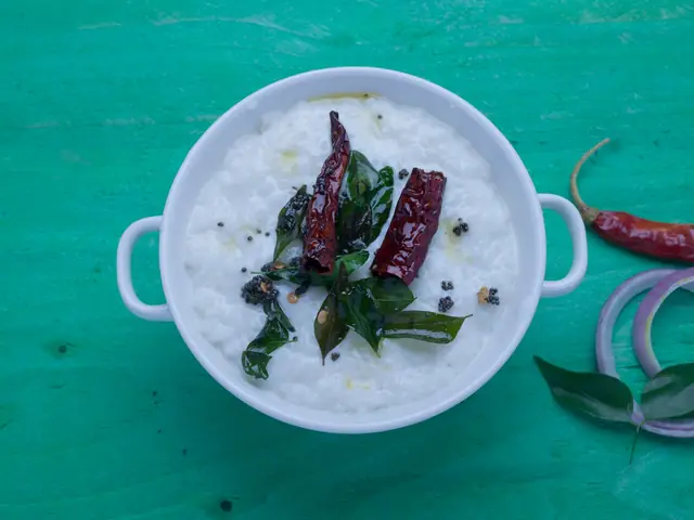 A bowl of tempered curd with curry leaves and red chillies for gut health