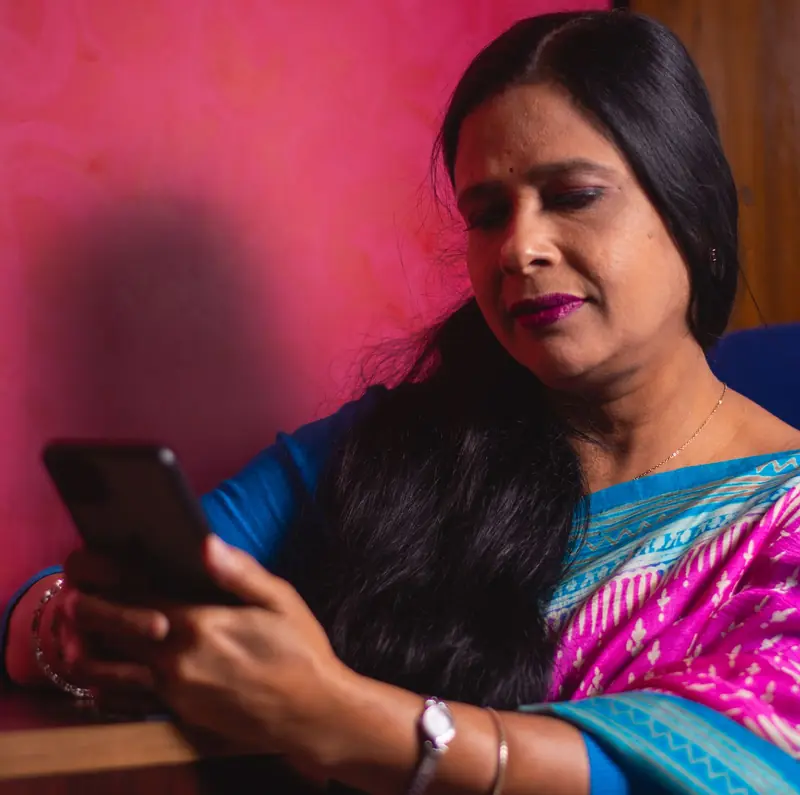 An Indian woman in a saree reading a message from her dietitian on her phone at home
